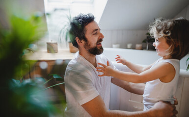 Wall Mural - Mature father with small daughter indoors at home, getting ready for a bath.