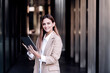 © Westend61 - Smiling young businesswoman with digital tablet standing at corridor