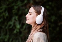 Young Female Professional With Eyes Closed Listening Music Through Wireless Headphones