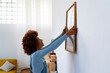 © Westend61 - Redhead woman installing photo frame on white wall