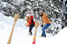 Smiling Man Gesturing By Girlfriend Playing On Snow During Winter