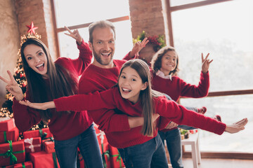 Poster - Photo of nice positive family father hold flying little girl mother son show v-sign in decorated x-mas home indoors