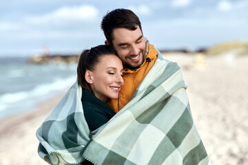 Sticker - love, relationship and people concept - happy smiling couple in warm blanket on autumn beach