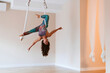 Sportswoman with arms outstretched doing aerial yoga in studio