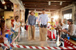 © luckybusiness - two young men, caucasian and afro-american,  jumping, racing in sacks at work with colleagues around cheering. teambuilding, improving productivity concept