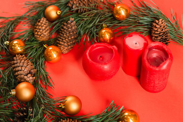 Canvas Print - high angle view of pine cones near green branches with christmas balls and candles on red