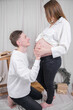 © SYARGEENKA - Caring husband talking to her pregnant wife's belly. Pregnancy, winter holidays and people concept