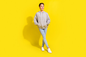 Wall Mural - Full length photo of cute brown hair young lady look empty space wear sportcloth jeans sneakers isolated on yellow background