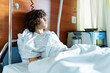 © Anna - Young teenager sitting in a hospital bed in a ward. Boy preparing for surgery. Sad  depressed child looking aside.  Urgent hospitalization.