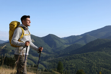 Wall Mural - Tourist with backpack and trekking poles hiking through mountains, space for text