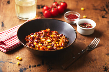 Wall Mural - Chili Con Carne with ground beef, beans and corn in dark bowl on wooden background. Mexican and Texas cuisine