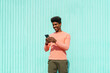 © VISTA by Westend61 - Smiling man using smart phone in front of turquoise wall during sunny day