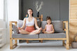 © Вадим Каштанов - Young mother with her little daughter sitting in lotus position on couch. Meditation and relaxation.