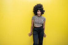 Surprised Afro Woman Standing In Front Of Yellow Wall