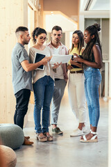 Canvas Print - Shot of multiethnic businesspeople working together while talking standing in a coworking place.