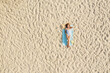 © New Africa - Woman sunbathing on beach towel at sandy coast, aerial view. Space for text