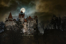 Moon In The Clouds Over Bran Castle, Transylvania, Romania. Medieval Building, Dracula's Castle. Mystical Night Landscape.