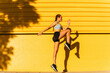 © VISTA by Westend61 - Young female athlete exercising by yellow wall during sunny day