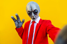 Portrait Of Man Wearing Alien Costume And Bright Red Suit Reaching Toward Camera