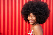 Cheerful Young Woman Smiling By Red Wall