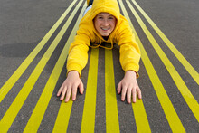 Smiling Boy Lying On Striped Yellow Road Markings