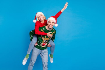 Sticker - Photo portrait funny couple wearing xmas outfit waving hands embracing piggyback isolated vibrant blue color background