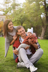 Sticker - Happy parents with their adorable baby on green grass in park