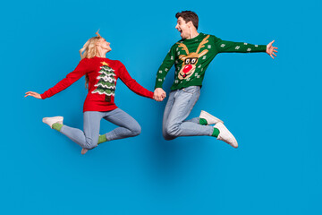 Poster - Full length photo of impressed young couple jump wear sweater jeans socks shoes isolated on blue background