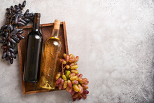 Two Wine Bottles With Grapes And Wineglasses On Old Gray Concrete Table Background With Copy Space. Red Wine With A Vine Branch. Wine Composition On Rustic Background. Mock Up.
