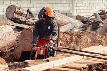 Lumberjack cutting tree trunk with giant chainsaw to make wooden planks