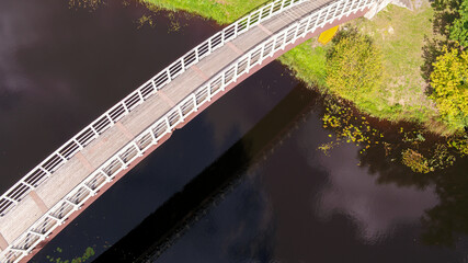 Sticker - Arching bridge over a deep blue river in greenery