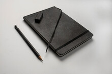 Black Notebook, Black Pencil And Black Eraser On White Background