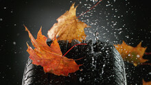 Car Tire With Falling Autumn Leaves And Splashing Water