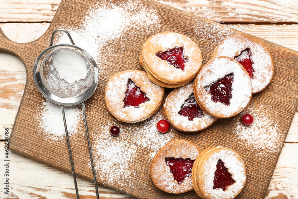 Board with tasty Linzer cookies, cranberry and powdered sugar on table