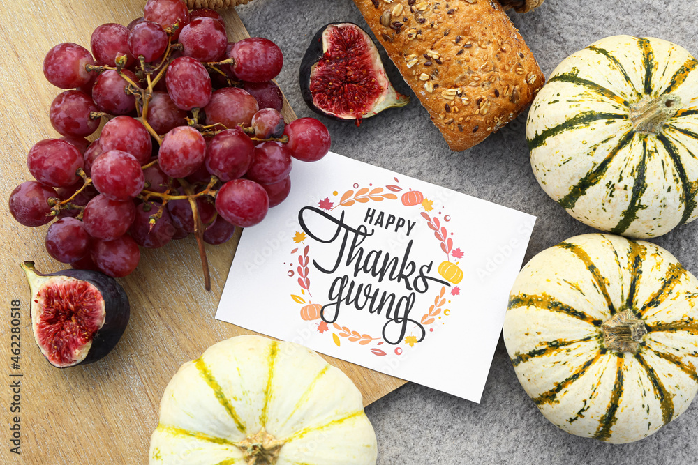 Pumpkins, bread, grape, figs and card with text HAPPY THANKSGIVING on plaid