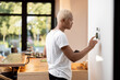© rh2010 - Latin man choosing temperature on thermostat. Young focused guy pushing button on smart home system. Concept of modern domestic lifestyle. Interior of kitchen in modern apartment.