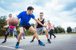 © Kzenon - Group of happy young people playing basketball on outdoor court