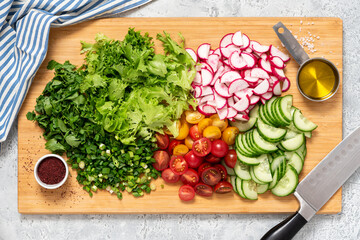 Cooking vegetable salad. Chopped vegetables and herbs on a cutting board top view. Diet or vegan food concept. Salad ingredients on a cutting board.