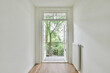 © Casa Media/Wirestock - Interior shot of a modern hallway in white tones with a wooden floor leading to a balcony