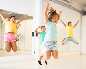 Wall Mural - Group of positive kids jumping while dancing together in studion.