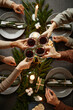 © Seventyfour - Top view background of four people enjoying Christmas dinner together and toasting with wine glasses while sitting by elegant dining table with candles