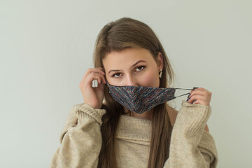 Shot of a young woman removing protective mask and spending time on white background at corona pandemic. Copy space. Woman taking off mask. Coronavirus ended. Quarantine is over concept.