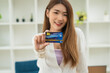 © PaeGAG - Young beautiful Asian woman smiling, showing, presenting credit card for making payment or paying online business, Pay a merchant or as a cash advance for goods, Cardholder or A person who owns a card