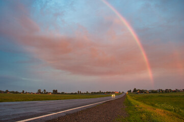 Wall Mural - stormy sky with rainbow over the road