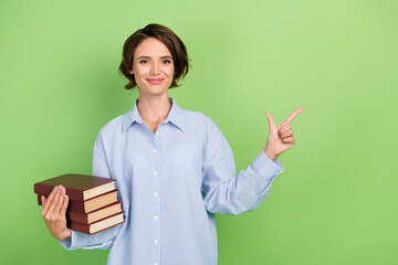 Poster - Photo of young woman happy positive smile hold book point finger empty space ad promo isolated over green color background