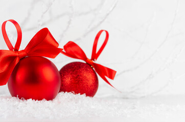 Wall Mural - Traditional christmas decoration - red glitter balls with ribbons, bows, closeup with blur in snow, white elegant soft light fairy winter forest, frosty branches, copy space. New Year background.