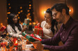 © Syda Productions - holidays, party and celebration concept - multiethnic group of happy friends having christmas dinner and opening presents at home