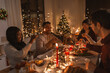© Syda Productions - holidays and celebration concept - multiethnic group of happy friends with sparklers having christmas dinner at home
