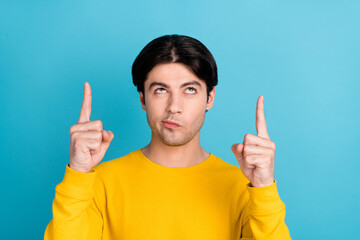 Poster - Photo of young man look indicate finger empty space advertise advise choose direct way recommend isolated over blue color background