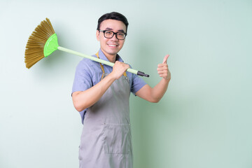 Young Asian man wearing apron posing on green background